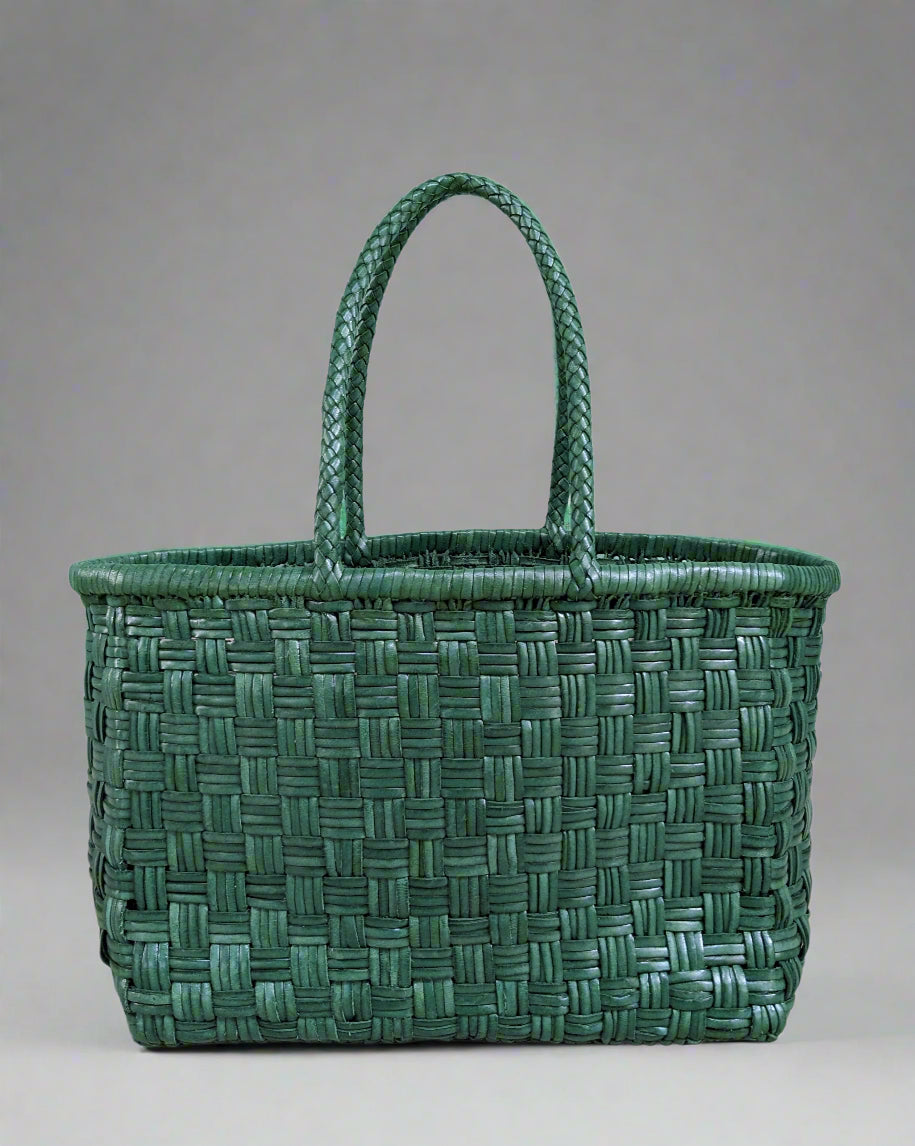 Green leather woven basket with handles on a light blue background