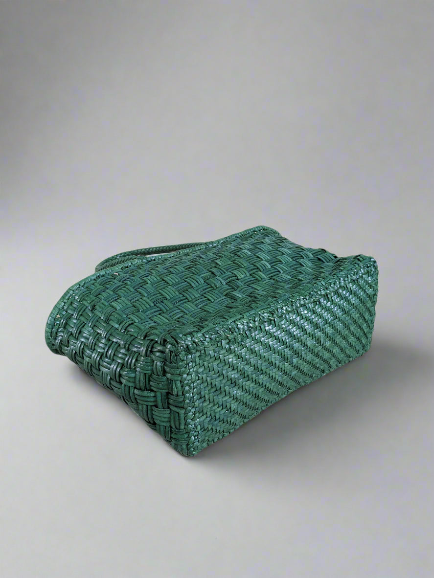 Green woven basket on a light wooden floor with a light blue wall in the background